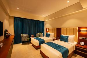 a hotel room with two beds and a desk at Hotel Classic Pavilion in Trivandrum