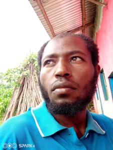 a man with a beard standing in front of a building at Tesfaye Gago in Jīma