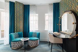 a bathroom with blue chairs and a vanity and a mirror at NYX Hotel Amsterdam Rembrandt Square in Amsterdam +27 photos