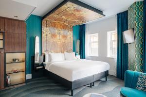 a bedroom with a large bed and a blue wall at NYX Hotel Amsterdam Rembrandt Square in Amsterdam