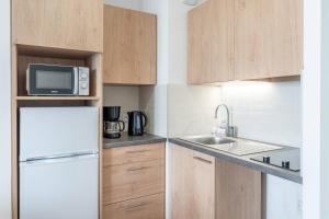 a small kitchen with a refrigerator and a sink at Zenitude Hôtel-Résidences Chambéry in Chambéry +33 photos