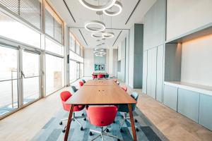 Karpaz Gate Marina Hotel في Ayia Trias: غرفة اجتماعات مكتبية بها طاولة طويلة وكراسي حمراء +40 صورة