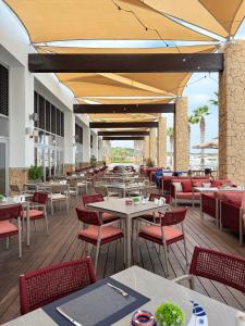 Karpaz Gate Marina Hotel في Ayia Trias: مطعم فارغ بطاولات وكراسي وطاولة