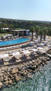 Karpaz Gate Marina Hotel في Ayia Trias: اطلالة جوية على المسبح مع الكراسي والمظلات