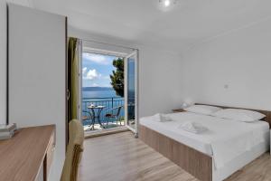 a white bedroom with a bed and a balcony at View Blue Apartments in Brela