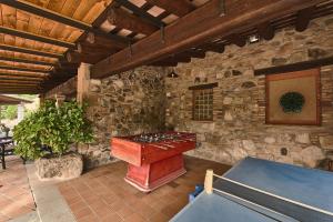 Una mesa de ping pong en una habitación con una pared de piedra. en Villa - Can Salarichs, en Riudarenes