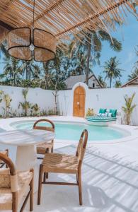 a patio with a table and chairs and a swimming pool at Lumora Boutique Villas in Gili Trawangan +16 photos