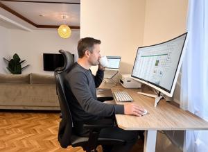 a man sitting at a desk with a computer with a cup of coffee at HOSHIYA Kamifurano in Kami-furano