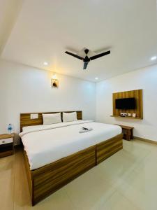 a bedroom with a large bed with a ceiling fan at Staymax Parassinikadavu in Parassinikadavu