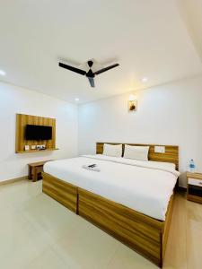 a bedroom with a large bed with a ceiling fan at Staymax Parassinikadavu in Parassinikadavu