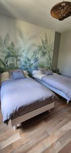 two beds in a bedroom with a mural of plants at Gîte Le repos du voyageur in Mary