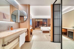 a bathroom with a sink and a bedroom at Orange Hotel Hangzhou Songcheng in Hangzhou