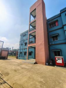 un edificio alto con un estacionamiento delante de él en Hotel Saksham, en Pākaur