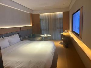ein Hotelzimmer mit Bett und Fernseher in der Unterkunft JI Hotel Nanjing Qinhuai Baixia High-tech Industrial Park in Nanjing