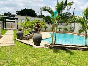 a swimming pool with palm trees next to a building at Longhorn Executive Apartments in Lusaka
