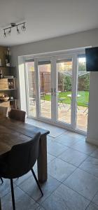 Hart's Place في Broughton Astley: غرفة معيشة مع طاولة وأبواب زجاجية منزلقة