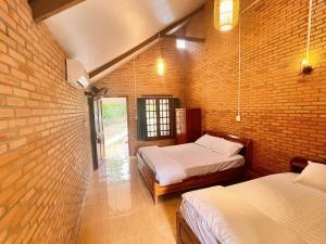 a room with two beds and a brick wall at Nam Cat Tien Retreat in Tân Phú