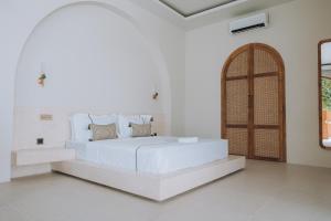 a white bedroom with a white bed and a wooden door at Lumora Boutique Villas in Gili Trawangan