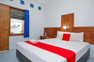 a bedroom with a large white bed with red accents at RedDoorz at Hotel Raditia Graha Yogyakarta in Yogyakarta +54 photos