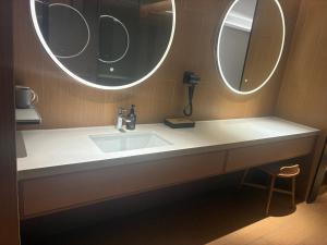 ein Badezimmer mit Waschbecken und zwei Spiegeln in der Unterkunft JI Hotel Nanjing Qinhuai Baixia High-tech Industrial Park in Nanjing