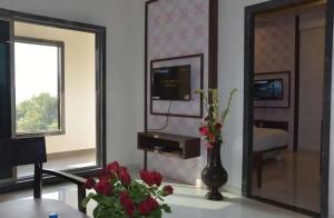 uma sala de estar com um espelho e um vaso com flores em Krushnai Resort em Kharakvasla