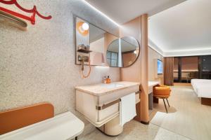 a bathroom with a sink and a mirror at Orange Hotel Hangzhou Songcheng in Hangzhou