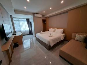 een slaapkamer met een groot wit bed en een bank bij Velin Pattaya Hotel in Ban Nong Chaeng