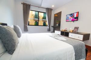 a bedroom with a white bed and a television at Ostro Hotel in Phnom Penh