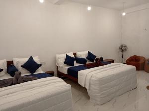 two beds with blue pillows in a room at Camellia Guest Inn in Ella