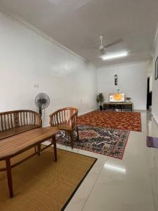 Una sala de estar con dos bancos de madera y una alfombra. en Hashim Homestay ISV 01003, en Mersing