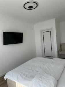 a white bedroom with a bed and a flat screen tv at White loft ЖК Престиж in Ternopilʼ