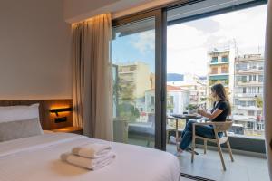Eine Frau sitzt auf einem Stuhl in einem Zimmer mit Fenster in der Unterkunft CENTRO Suites in Kalamata