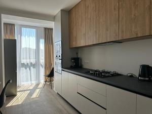a kitchen with white cabinets and a black counter top at White loft ЖК Престиж in Ternopilʼ
