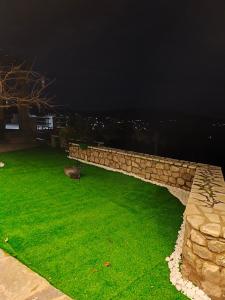 a stone retaining wall with green grass at night at Φεγγαρόπετρα -ΠΑΝΣΕΛΗΝΟΣ in Kalívia
