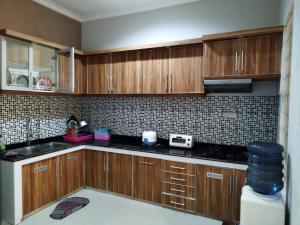 a kitchen with wooden cabinets and black counter tops at Villa Kusuma Pinus M10 in Batu +3 photos