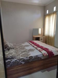 a bedroom with a bed with a wooden frame at Villa Kusuma Pinus M10 in Batu