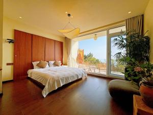 a bedroom with a large bed and a large window at Qingdao Momer Cliff Ocean View Villas in Qingdao