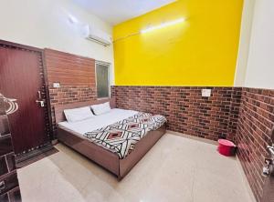 1 dormitorio pequeño con 1 cama en una pared de ladrillo en shri radha ji guest House, en Vrindāvan