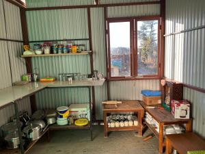 a kitchen with shelves and a table in a room at Sawra Homestay in Chakrāta