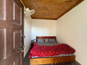 a bedroom with a bed with a red comforter and a wooden door at Sawra Homestay in Chakrāta