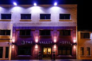 una fachada de hotel por la noche con luces en The Valley Hotel & Carriage Gardens en Fivemiletown