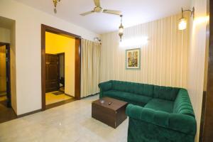 a living room with a green couch and a table at Nestoa Suites - Benson Town in Bangalore
