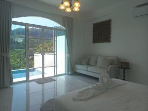 a white room with a bed and a couch and a window at ม่อนคูณตะวันฮิลล์ลอดจ์ in Ban Tai