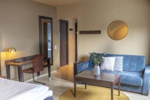 a living room with a blue couch and a table at Scandic Victoria Florø in Florø +37 photos