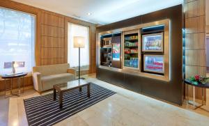 a living room with a couch a chair and a refrigerator at NH Sport in Zaragoza