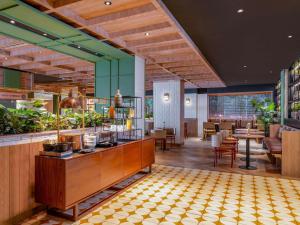 Un restaurante con barra, mesas y sillas. en Mercure Jakarta Sabang, en Yakarta