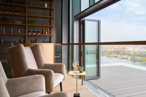 Una sala de estar con dos sillas y una mesa con copas de vino. en Hotel Indigo Berlin - East Side Gallery, en Berlín