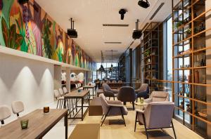 un restaurante con mesas, sillas y ventanas en Hotel Indigo Berlin - East Side Gallery, en Berlín