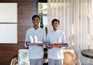 two men in white uniforms holding a tray of food at LohonoStays Amani Villa 10A in Coonoor