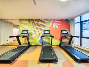 a gym with three treadmills and a colorful wall at Orange Hotel Hangzhou Songcheng in Hangzhou